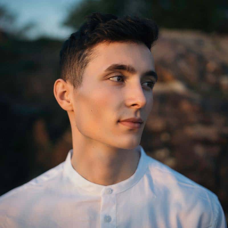 A young man in a white shirt, who appears to be a Functional Medicine Doctor in Los Angeles, is staring at the camera.