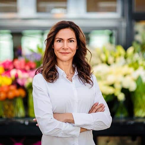 A woman standing in front of a flower shop.